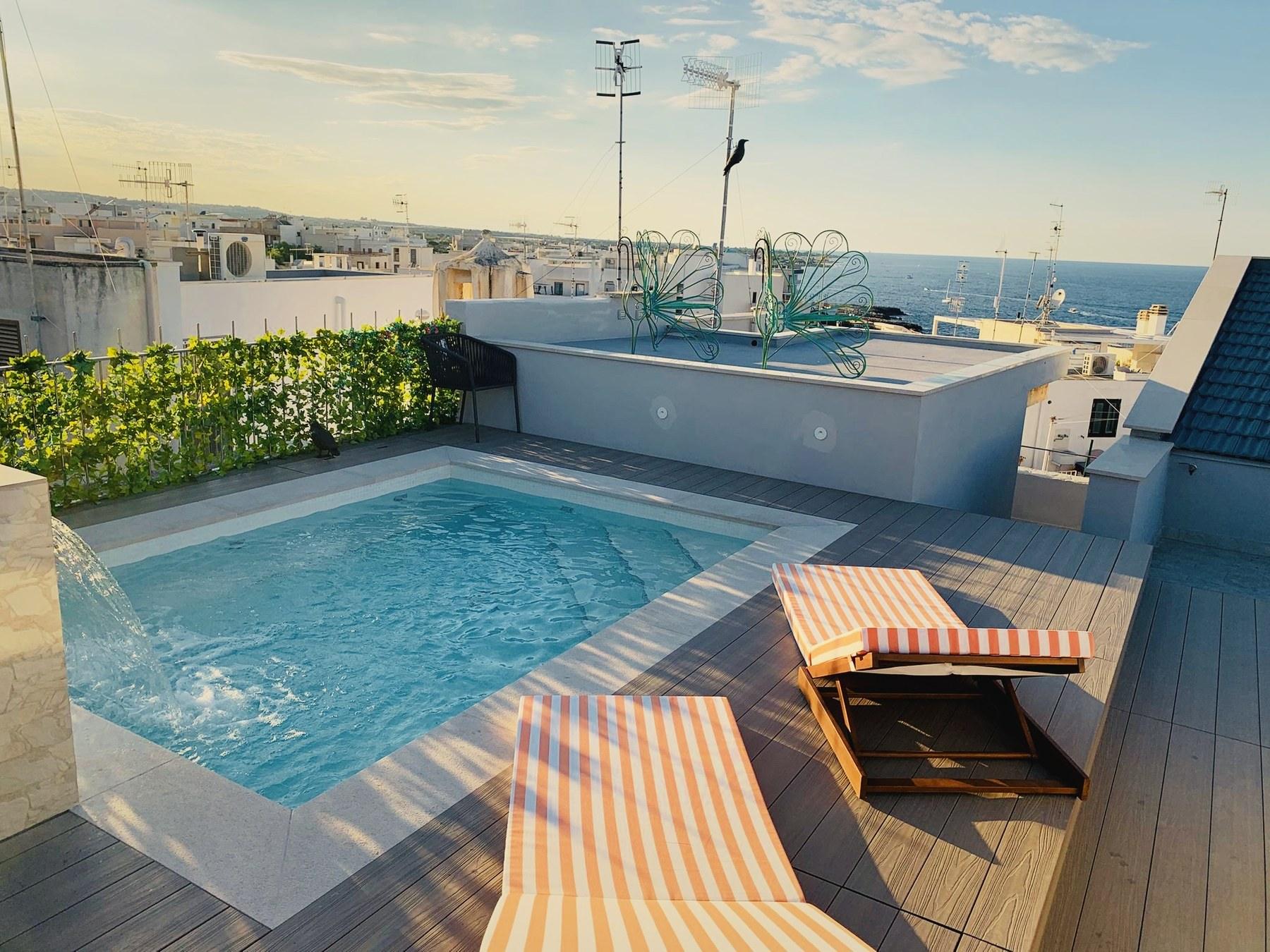 The heated rooftop pool above Polignano a Mare, its waterfall running into the water.